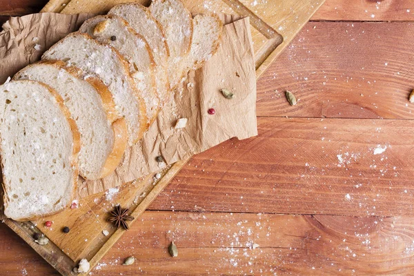 Taze ve güzel kokulu beyaz ekmek dilimlenmiş ve bir ahşap zemin üzerine yalancı. Biraz baharat kendisine eklenmiş ve aynı zamanda kraft kağıt üzerinde yatıyor. Gluten-Alerjik. Kavramsal gıda fotoğraf.