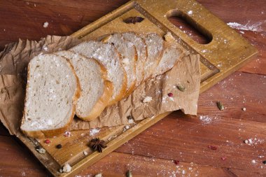 Taze ve güzel kokulu beyaz ekmek dilimlenmiş ve bir ahşap zemin üzerine yalancı. Biraz baharat kendisine eklenmiş ve aynı zamanda kraft kağıt üzerinde yatıyor. Gluten-Alerjik. Kavramsal gıda fotoğraf.