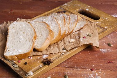 Taze ve güzel kokulu beyaz ekmek dilimlenmiş ve bir ahşap zemin üzerine yalancı. Biraz baharat kendisine eklenmiş ve aynı zamanda kraft kağıt üzerinde yatıyor. Gluten-Alerjik. Kavramsal gıda fotoğraf.
