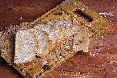 Taze ve güzel kokulu beyaz ekmek dilimlenmiş ve bir ahşap zemin üzerine yalancı. Biraz baharat kendisine eklenmiş ve aynı zamanda kraft kağıt üzerinde yatıyor. Gluten-Alerjik. Kavramsal gıda fotoğraf.