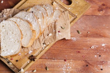 Taze ve güzel kokulu beyaz ekmek dilimlenmiş ve bir ahşap zemin üzerine yalancı. Biraz baharat kendisine eklenmiş ve aynı zamanda kraft kağıt üzerinde yatıyor. Gluten-Alerjik. Kavramsal gıda fotoğraf.