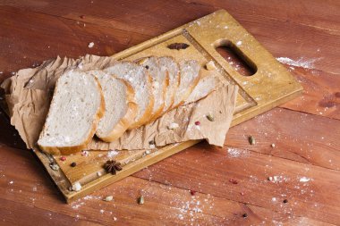 Taze ve güzel kokulu beyaz ekmek dilimlenmiş ve bir ahşap zemin üzerine yalancı. Biraz baharat kendisine eklenmiş ve aynı zamanda kraft kağıt üzerinde yatıyor. Gluten-Alerjik. Kavramsal gıda fotoğraf.