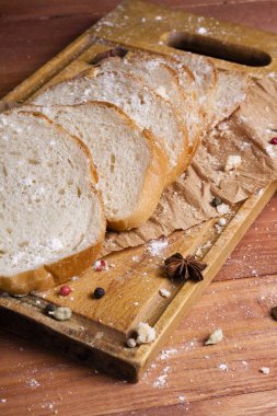 Taze ve güzel kokulu beyaz ekmek dilimlenmiş ve bir ahşap zemin üzerine yalancı. Biraz baharat kendisine eklenmiş ve aynı zamanda kraft kağıt üzerinde yatıyor. Gluten-Alerjik. Kavramsal gıda fotoğraf.