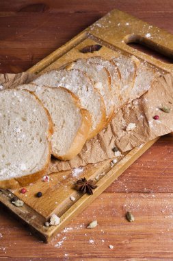 Taze ve güzel kokulu beyaz ekmek dilimlenmiş ve bir ahşap zemin üzerine yalancı. Biraz baharat kendisine eklenmiş ve aynı zamanda kraft kağıt üzerinde yatıyor. Gluten-Alerjik. Kavramsal gıda fotoğraf.