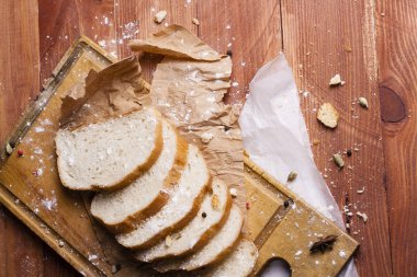 Taze ve güzel kokulu beyaz ekmek dilimlenmiş ve bir ahşap zemin üzerine yalancı. Biraz baharat kendisine eklenmiş ve aynı zamanda kraft kağıt üzerinde yatıyor. Gluten-Alerjik. Kavramsal gıda fotoğraf.