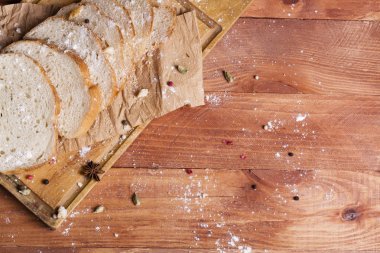 Taze ve güzel kokulu beyaz ekmek dilimlenmiş ve bir ahşap zemin üzerine yalancı. Biraz baharat kendisine eklenmiş ve aynı zamanda kraft kağıt üzerinde yatıyor. Gluten-Alerjik. Kavramsal gıda fotoğraf.