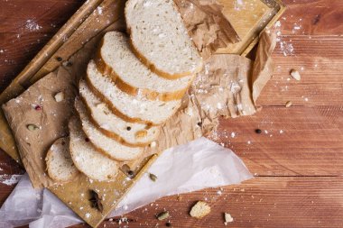 Taze ve güzel kokulu beyaz ekmek dilimlenmiş ve bir ahşap zemin üzerine yalancı. Biraz baharat kendisine eklenmiş ve aynı zamanda kraft kağıt üzerinde yatıyor. Gluten-Alerjik. Kavramsal gıda fotoğraf.