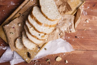 Taze ve güzel kokulu beyaz ekmek dilimlenmiş ve bir ahşap zemin üzerine yalancı. Biraz baharat kendisine eklenmiş ve aynı zamanda kraft kağıt üzerinde yatıyor. Gluten-Alerjik. Kavramsal gıda fotoğraf.