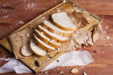 Taze ve güzel kokulu beyaz ekmek dilimlenmiş ve bir ahşap zemin üzerine yalancı. Biraz baharat kendisine eklenmiş ve aynı zamanda kraft kağıt üzerinde yatıyor. Gluten-Alerjik. Kavramsal gıda fotoğraf.
