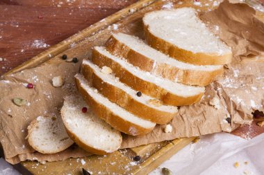 Taze ve güzel kokulu beyaz ekmek dilimlenmiş ve bir ahşap zemin üzerine yalancı. Biraz baharat kendisine eklenmiş ve aynı zamanda kraft kağıt üzerinde yatıyor. Gluten-Alerjik. Kavramsal gıda fotoğraf.