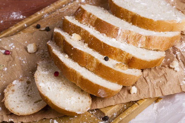 Taze ve güzel kokulu beyaz ekmek dilimlenmiş ve bir ahşap zemin üzerine yalancı. Biraz baharat kendisine eklenmiş ve aynı zamanda kraft kağıt üzerinde yatıyor. Gluten-Alerjik. Kavramsal gıda fotoğraf.