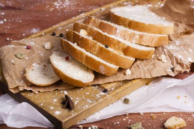 Taze ve güzel kokulu beyaz ekmek dilimlenmiş ve bir ahşap zemin üzerine yalancı. Biraz baharat kendisine eklenmiş ve aynı zamanda kraft kağıt üzerinde yatıyor. Gluten-Alerjik. Kavramsal gıda fotoğraf.