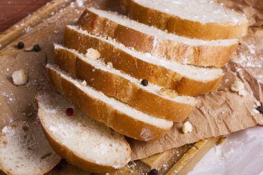 Taze ve güzel kokulu beyaz ekmek dilimlenmiş ve bir ahşap zemin üzerine yalancı. Biraz baharat kendisine eklenmiş ve aynı zamanda kraft kağıt üzerinde yatıyor. Gluten-Alerjik. Kavramsal gıda fotoğraf.