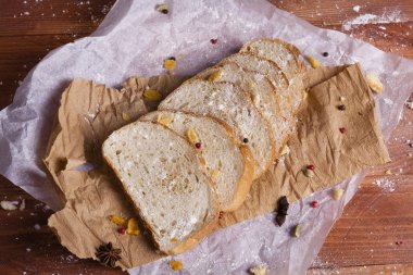 Taze ve güzel kokulu beyaz ekmek dilimlenmiş ve bir ahşap zemin üzerine yalancı. Biraz baharat kendisine eklenmiş ve aynı zamanda kraft kağıt üzerinde yatıyor. Gluten-Alerjik. Kavramsal gıda fotoğraf.