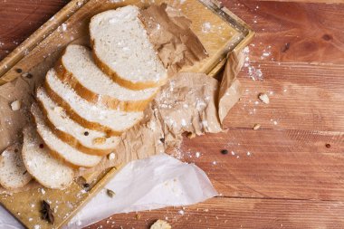 Taze ve güzel kokulu beyaz ekmek dilimlenmiş ve bir ahşap zemin üzerine yalancı. Biraz baharat kendisine eklenmiş ve aynı zamanda kraft kağıt üzerinde yatıyor. Gluten-Alerjik. Kavramsal gıda fotoğraf.