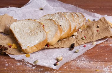 Taze ve güzel kokulu beyaz ekmek dilimlenmiş ve bir ahşap zemin üzerine yalancı. Biraz baharat kendisine eklenmiş ve aynı zamanda kraft kağıt üzerinde yatıyor. Gluten-Alerjik. Kavramsal gıda fotoğraf.