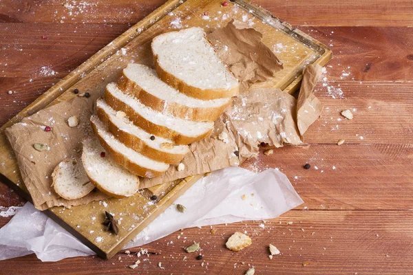 Taze ve güzel kokulu beyaz ekmek dilimlenmiş ve bir ahşap zemin üzerine yalancı. Biraz baharat kendisine eklenmiş ve aynı zamanda kraft kağıt üzerinde yatıyor. Gluten-Alerjik. Kavramsal gıda fotoğraf.