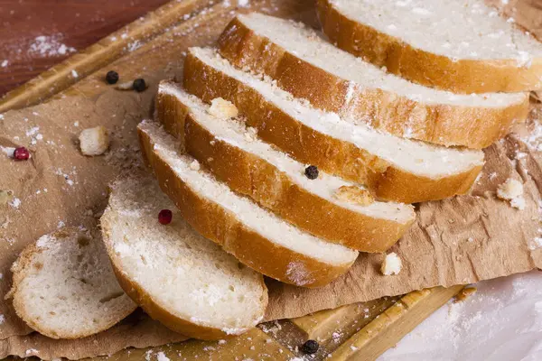 Taze ve güzel kokulu beyaz ekmek dilimlenmiş ve bir ahşap zemin üzerine yalancı. Biraz baharat kendisine eklenmiş ve aynı zamanda kraft kağıt üzerinde yatıyor. Gluten-Alerjik. Kavramsal gıda fotoğraf.