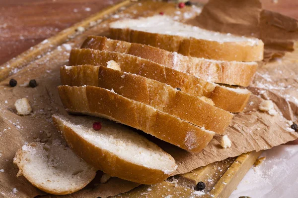 Taze ve güzel kokulu beyaz ekmek dilimlenmiş ve bir ahşap zemin üzerine yalancı. Biraz baharat kendisine eklenmiş ve aynı zamanda kraft kağıt üzerinde yatıyor. Gluten-Alerjik. Kavramsal gıda fotoğraf.