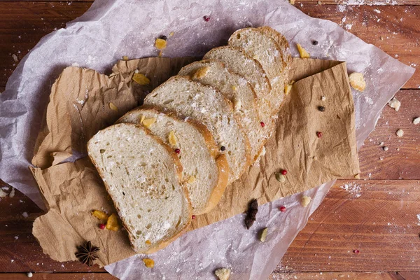 Taze ve güzel kokulu beyaz ekmek dilimlenmiş ve bir ahşap zemin üzerine yalancı. Biraz baharat kendisine eklenmiş ve aynı zamanda kraft kağıt üzerinde yatıyor. Gluten-Alerjik. Kavramsal gıda fotoğraf.