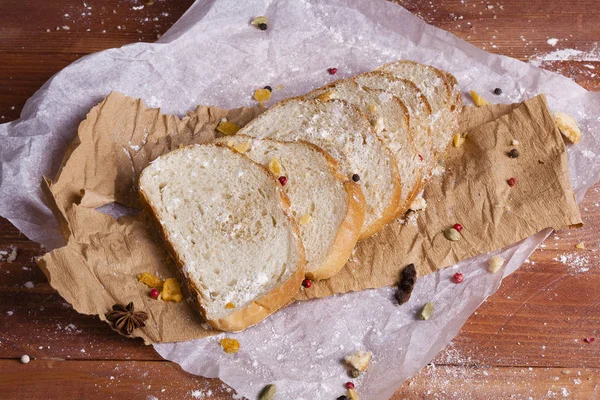 Taze ve güzel kokulu beyaz ekmek dilimlenmiş ve bir ahşap zemin üzerine yalancı. Biraz baharat kendisine eklenmiş ve aynı zamanda kraft kağıt üzerinde yatıyor. Gluten-Alerjik. Kavramsal gıda fotoğraf.