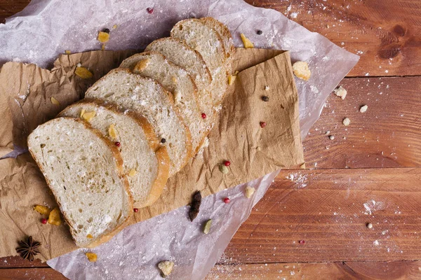 Taze ve güzel kokulu beyaz ekmek dilimlenmiş ve bir ahşap zemin üzerine yalancı. Biraz baharat kendisine eklenmiş ve aynı zamanda kraft kağıt üzerinde yatıyor. Gluten-Alerjik. Kavramsal gıda fotoğraf.