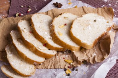 Taze ve güzel kokulu beyaz ekmek dilimlenmiş ve bir ahşap zemin üzerine yalancı. Biraz baharat kendisine eklenmiş ve aynı zamanda kraft kağıt üzerinde yatıyor. Gluten-Alerjik. Kavramsal gıda fotoğraf.