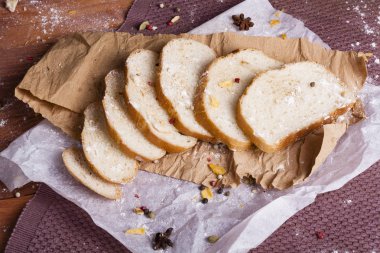 Taze ve güzel kokulu beyaz ekmek dilimlenmiş ve bir ahşap zemin üzerine yalancı. Biraz baharat kendisine eklenmiş ve aynı zamanda kraft kağıt üzerinde yatıyor. Gluten-Alerjik. Kavramsal gıda fotoğraf.