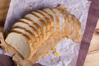 Taze ve güzel kokulu beyaz ekmek dilimlenmiş ve bir ahşap zemin üzerine yalancı. Biraz baharat kendisine eklenmiş ve aynı zamanda kraft kağıt üzerinde yatıyor. Gluten-Alerjik. Kavramsal gıda fotoğraf.