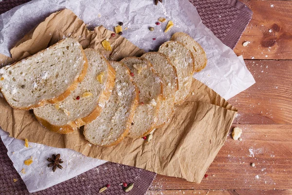 Taze ve güzel kokulu beyaz ekmek dilimlenmiş ve bir ahşap zemin üzerine yalancı. Biraz baharat kendisine eklenmiş ve aynı zamanda kraft kağıt üzerinde yatıyor. Gluten-Alerjik. Kavramsal gıda fotoğraf.