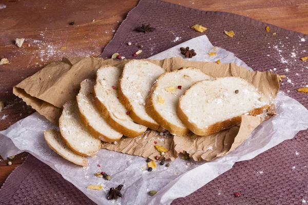 Taze ve güzel kokulu beyaz ekmek dilimlenmiş ve bir ahşap zemin üzerine yalancı. Biraz baharat kendisine eklenmiş ve aynı zamanda kraft kağıt üzerinde yatıyor. Gluten-Alerjik. Kavramsal gıda fotoğraf.