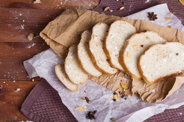 Taze ve güzel kokulu beyaz ekmek dilimlenmiş ve bir ahşap zemin üzerine yalancı. Biraz baharat kendisine eklenmiş ve aynı zamanda kraft kağıt üzerinde yatıyor. Gluten-Alerjik. Kavramsal gıda fotoğraf.