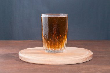 Bir ahşap stand kahverengi ahşap zemin üzerinde bir yüksek cam bardakta Light bira