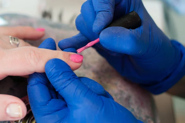 Proceso manicura uñas de color rosa lacado salón de spa. Servicios de belleza conceptual. Hermosas manos femeninas de cerca — Foto de Stock