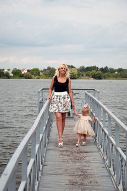 Anne ve kızı yürüyüş, eğleniyor, nehrin kıyısında parkta oynarken.