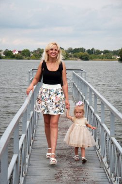 Anne ve kızı yürüyüş, eğleniyor, nehrin kıyısında parkta oynarken.