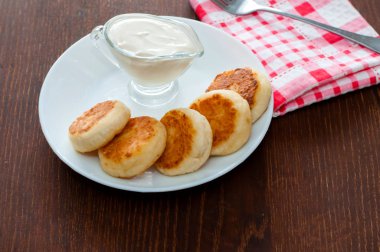 Çatallı pembe peçete üzerinde beyaz bir tabak ta ekşi kremalı peynirli krep