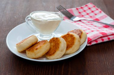 Bir çatal ile pembe bir peçete üzerinde beyaz bir tabak üzerinde ekşi krema ile Peynir krep, yan görünüm