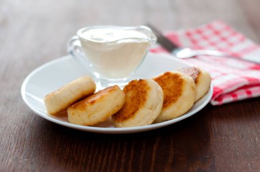 Bir çatal, yan görünümü ile pembe bir peçete üzerinde beyaz bir tabak üzerinde ekşi krema ile Peynir krep. Menü tasarımı için kullanılabilir.