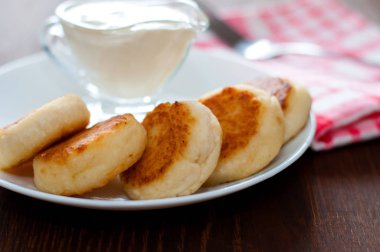 Bir çatal ile pembe bir peçete üzerinde beyaz bir tabak üzerinde ekşi krema ile Peynir krep, yakın çekim. Menü tasarımı için kullanılabilir.