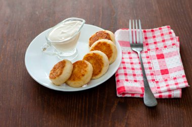 Bir çatal ile pembe bir peçete üzerinde beyaz bir tabak üzerinde ekşi krema ile Peynir krep. Menü tasarımı için kullanılabilir.