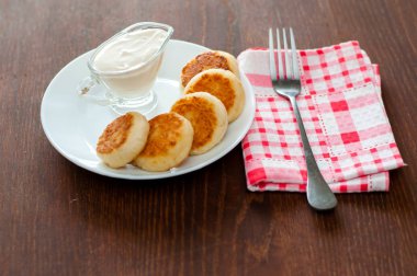 Bir çatal ile pembe bir peçete üzerinde beyaz bir tabak üzerinde ekşi krema ile Peynir krep. Menü tasarımı için kullanılabilir.