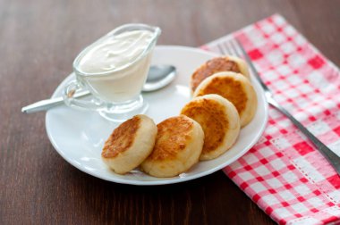 Üstten beyaz bir tabak görünümünde ekşi krema ile kızarmış peynir krep. Menü tasarımı için kullanılabilir.