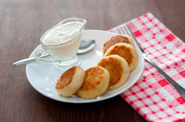 Üstten beyaz bir tabak görünümünde ekşi krema ile kızarmış peynir krep. Menü tasarımı için kullanılabilir.