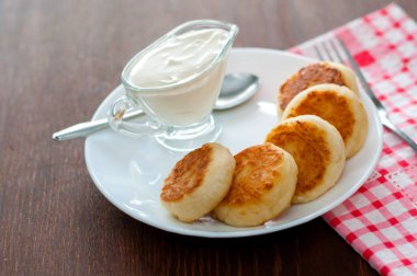 Üstten beyaz bir tabak görünümünde ekşi krema ile kızarmış peynir krep. Menü tasarımı için kullanılabilir.