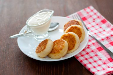 Üstten beyaz bir tabak görünümünde ekşi krema ile kızarmış peynir krep. Menü tasarımı için kullanılabilir.