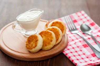 Bir çatal ile ahşap bir tahta üzerinde ekşi krema ile Peynir krep. Menü tasarımı, mutfak siteleri için kullanılabilir.