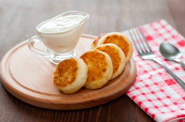 Bir çatal ile ahşap bir tahta üzerinde ekşi krema ile Peynir krep. Menü tasarımı, mutfak siteleri için kullanılabilir.