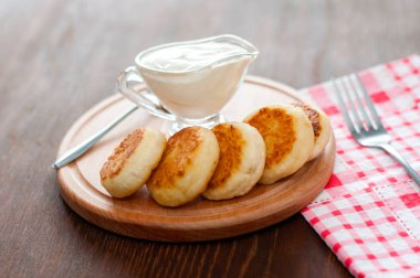 Ahşap bir tahta üzerinde ekşi krema ile Peynir krep, bir çatal ve peçete yatay formatında.