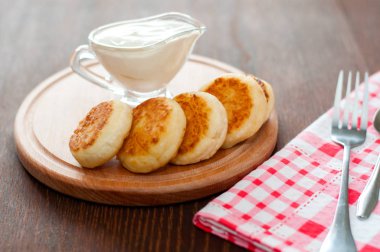 Ahşap bir tahta üzerinde ekşi krema ile Peynir krep, bir çatal ve peçete yatay formatında.